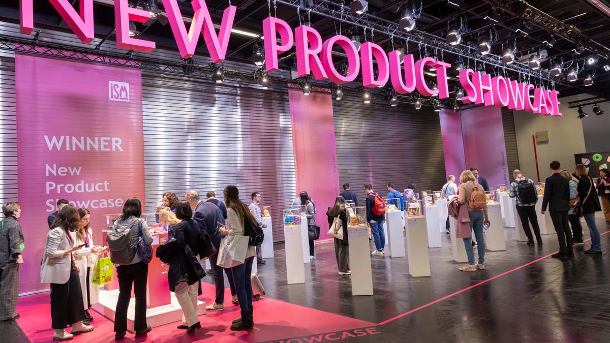 Visitors to ISM in Cologne discovering innovative products in the New Product Showcase under large plastic, pink-coloured lettering.